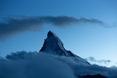 白天多云的天空下，山被雪覆盖